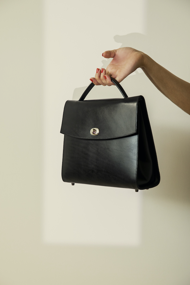 Modell Berny Frauenhand hält eine klassische Damentasche in schwarz