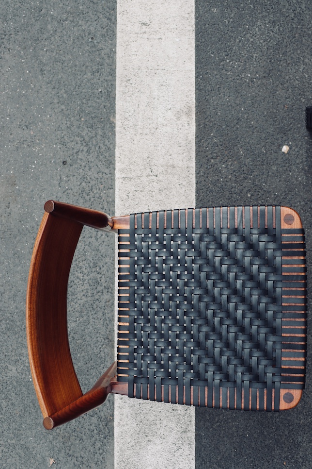 Ansicht eines mit schwarzen Lederriemen im Köpermuster bespannten Designerstuhls